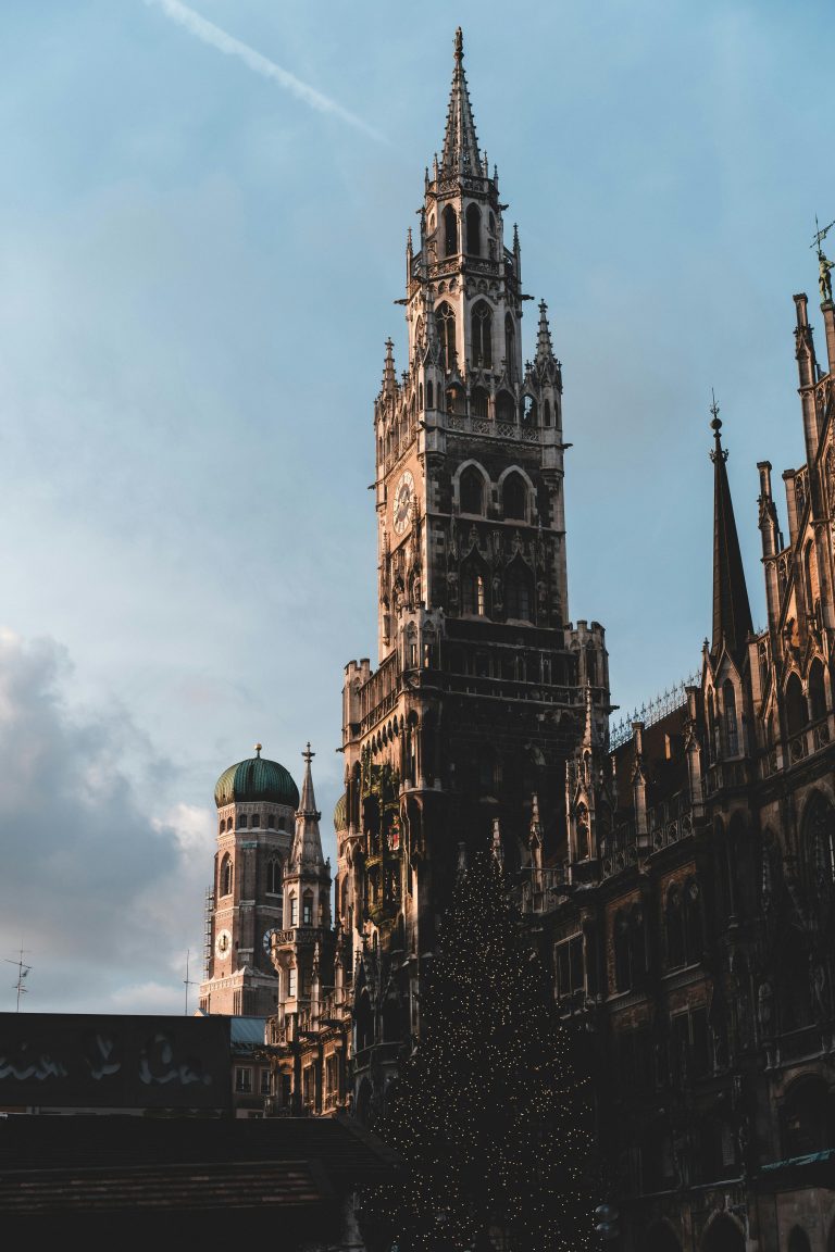 Dramatic view of Marienplatz showcasing Gothic architecture and towers at sunset in Munich, Germany.